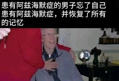 这是一张文字加注的真人静态照片，图片上方的黑色背景区域配有白色文字：“患有阿兹海默症的男子忘了自己患有阿兹海默症，并恢复了所有的记忆”。画面主体是一位戴眼镜的老年男性，他面带笑容，神情愉悦地坐在椅子上，旁边有一位穿着红色上衣的人，一只手放在老人的胸口处，另一只手搭在老人肩膀上，动作看起来像是在陪伴或安抚老人。背景是温馨的室内家居场景，能看到深色的桌子，桌上摆放着玻璃装饰摆件、深色花瓶等物品。配文存在逻辑上的趣味矛盾：阿兹海默症的典型症状包含记忆障碍，“忘记自己患病”本身是病症引发的记忆缺失表现，而非真正恢复了所有记忆，这段配文用看似惊喜的表述制造出带有黑色幽默的悖论效果。