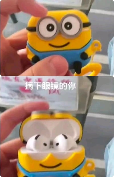 这是一张上下拼接的对比梗图，上图展示了一个还原《神偷奶爸》中小黄人形象的蓝牙耳机保护壳，它有着小黄人标志性的大眼睛、蓝色背带裤，正被手指捏着，表情微笑；下图是打开该保护壳后的样子，里面的白色耳机摆放位置与形态恰好组成了类似眯缝眼的效果，搭配配文“摘下眼镜的你”，生动调侃了近视人群摘下眼镜后视线模糊、眼睛看起来无神的日常状态，用趣味的周边设计制造出强烈的共鸣感。