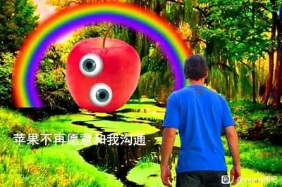 这是一张经过P图改编的静态网络梗图，画面背景是充满生机的林间溪流场景，茂密的绿植环绕着蜿蜒的溪流，一道色彩鲜艳的彩虹横跨在画面上方，营造出梦幻的自然氛围。画面的视觉焦点之一是被P上人类眼睛的红色苹果，它悬浮在溪流上方，拟人化的形象显得荒诞又滑稽；画面右侧，一名穿着蓝色短袖T恤的男子背对镜头站立，似乎正面对着这个拟人苹果。画面下方配有白色文字“苹果不再愿意和我沟通”，将苹果拟人化，用无厘头的方式表达出一种被对象（可能代指某个人、事物）拒绝沟通的无奈与搞笑情绪，属于典型的网络搞笑创作，通过违和的拟人化元素制造笑点。