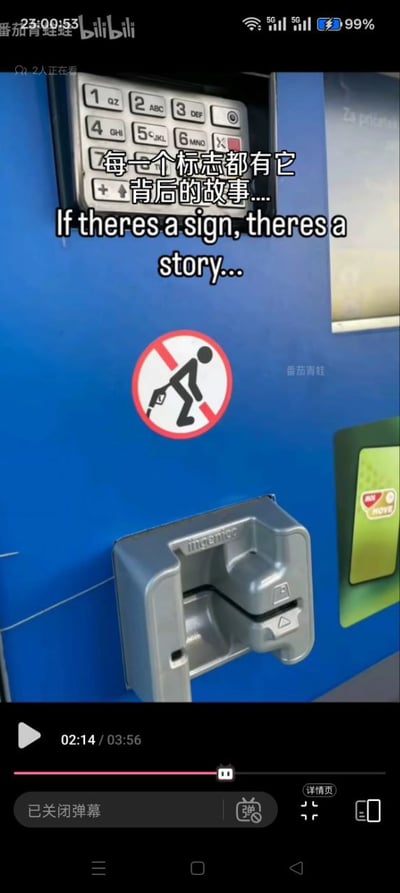 这是一张来自哔哩哔哩的视频截图，画面主体是国外蓝色自助加油机的局部：上方是加油机的数字密码键盘，中部印有一个禁止标志，标志图案为一个人形将加油枪插在自身下半身位置，被红圈斜杠标记为禁止，而这个标志刚好位于银行卡刷卡槽的正上方，图案和位置的巧合形成了低俗搞笑的效果；图上叠加了中英文字幕“每一个标志都有它背后的故事.... If theres a sign, theres a story...”，截图底部显示视频播放进度为02:14/03:56，左上角标注了UP主名称和哔哩哔哩平台标识。