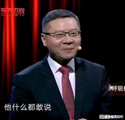 图片中是一位穿着深色西装、红色领带和戴着眼镜的中年男性，他站在红色幕布前，佩戴着麦克风，似乎正在电视节目中讲话或主持。图片底部有文字“他什么都敢说”，暗示这个人以敢于直言著称。