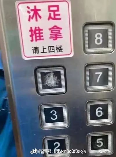这是一张实拍的电梯按键面板照片，面板左上角贴有白底粉边的提示贴纸，红色大字标注服务项目为沐足推拿，下方黑色小字提示消费者前往四楼消费，然而对应四楼位置的电梯按键表面已经被按得碎裂发白，按键上的数字标识完全不可见，旁边2、3、5、6、7、8楼层的按键都完好清晰，二者形成强烈反差，侧面暗示前往该场所消费的人数极多，充满趣味笑点。