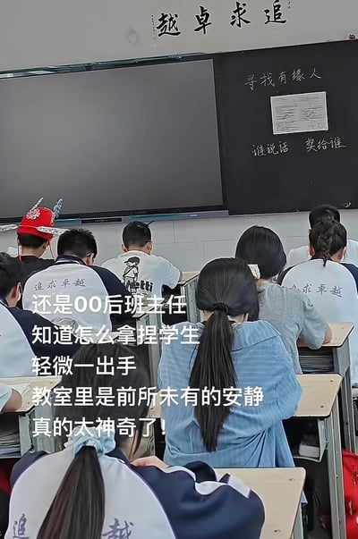 这是一张教室场景的照片，学生们正坐在课桌前。黑板上写着'寻找有缘人'和'谁说话 奖给谁'的字样。一名学生戴着红色的传统帽子，显得格外醒目。学生们穿着印有'追求卓越'字样的校服。图片传达了00后班主任独特的课堂管理方式，通过巧妙的方法让教室保持安静。