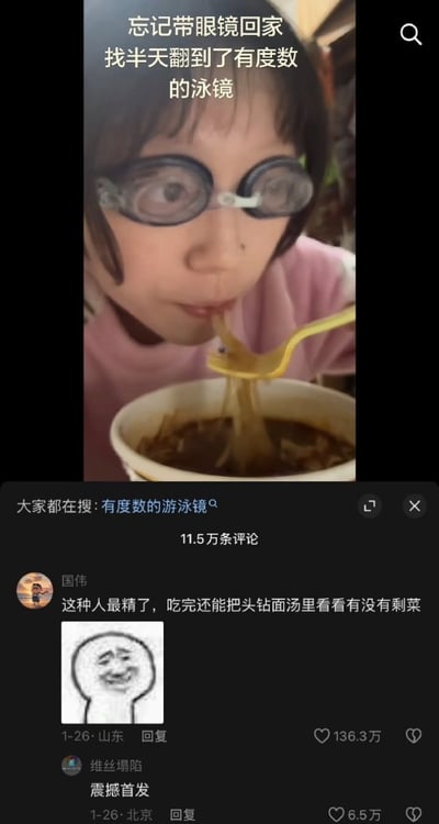 图片上半部分为一名戴着有度数泳镜的人正在用黄色勺子吃面条，上方文字说明“忘记带眼镜回家 找半天翻到了有度数的泳镜”，展现了近视人群忘记带眼镜后用泳镜应急的搞笑日常。下半部分为社交媒体评论区截图，显示用户“国伟”的热门评论：“这种人最精了，吃完还能把头钻面汤里看看有没有剩菜”，并配有一个歪嘴笑的meme表情包，评论获136.3万点赞，另有“震撼首发”的评论。整体场景轻松幽默，体现了网友的调侃与共鸣。