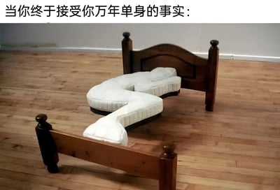图片上方配有文字“当你终于接受你万年单身的事实：”，下方是一张木质床，床垫呈现出独特的弯曲形状，仿佛在自行拥抱，营造出一种“单身也能自我安慰”的幽默效果。房间内为木质地板和浅色墙壁，整体场景简洁，通过拟人化的床垫形态，调侃了接受长期单身状态后的自我调适与释然心态。