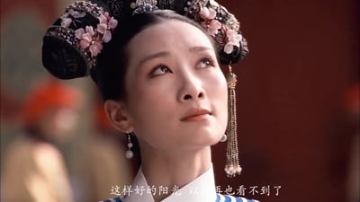 这是电视剧《后宫·甄嬛传》的影视截图，画面主体是角色安陵容，她头戴装饰有粉色花朵与珍珠流苏的清代旗头，抬头向上仰望，眼神带着怅惘又小心翼翼的情绪，画面底部配有台词字幕“这样好的阳光 以后再也看不到了”。该场景原本是安陵容被禁足后发出的感叹，现在被网友用来契合“偷感”这一网络热词的含义，成为热门表情包。