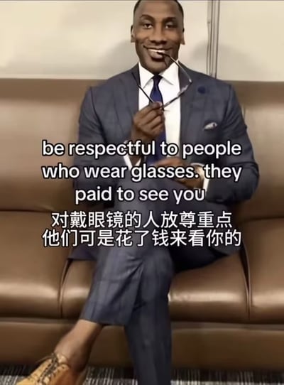 这是一张搞笑梗图，画面主体为一名身着深蓝色西装、白色衬衫搭配深蓝色领带的黑人男性，他翘着二郎腿坐在棕色皮质沙发上，右手举着一副眼镜放在嘴边，面带戏谑的笑意。画面上叠加了中英双字的文字内容，英文为“be respectful to people who wear glasses. they paid to see you”，对应中文翻译为“对戴眼镜的人放尊重点 他们可是花了钱来看你的”，利用戴眼镜的人配镜需要付费的常识制造双关笑点，将“配眼镜花钱才能看清他人”和“花钱买票看某人”的语义做巧妙结合，调侃意味浓厚。