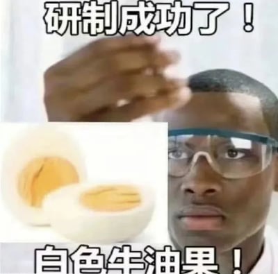 图片中一位戴着安全护目镜的真人男性，表情严肃，抬手做出展示动作。画面左侧嵌入了一张被切开的煮鸡蛋图片（蛋白白色，蛋黄黄色）。图片上方有文字“研制成功了！”，下方有文字“白色牛油果！”，通过将煮鸡蛋幽默地称为“白色牛油果”制造笑点，属于搞笑类图文混排 meme。