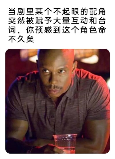这是一张用来调侃影视剧套路的梗图，上方配文点明了影视创作里的经典规律：原本戏份稀少的不起眼配角，一旦突然获得大量互动戏份和台词，往往意味着该角色即将在剧情里死亡，也就是观众常说的“领盒饭”。下方搭配的美剧剧照中，一位黑人男性眼神瞪大，表情惊讶又带着凝重，身体前倾双手握着透明杯子，这个神态既契合观众看到这类剧情时的反应，也仿佛角色自身预感到了即将到来的命运，让这个梗的调侃效果更强烈，能引发众多追剧观众的共鸣。