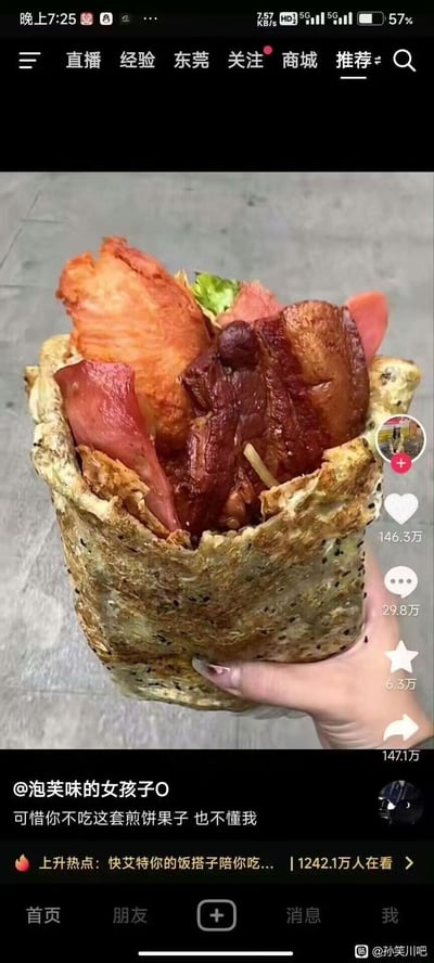 这是一张抖音平台的短视频截图，画面主体是一只手拿着一个分量超足的豪华版煎饼果子，煎饼外皮带有黑芝麻，里面塞满了大块卤五花肉、炸鸡排、火腿片和少量生菜，食材堆得满满当当，看起来十分硬核有食欲。视频配文为“可惜你不吃这套煎饼果子 也不懂我”，借这份超豪华的煎饼果子，表达自己的小众喜好不被他人理解的情绪，图中没有双关、谐音梗或暗示内容。