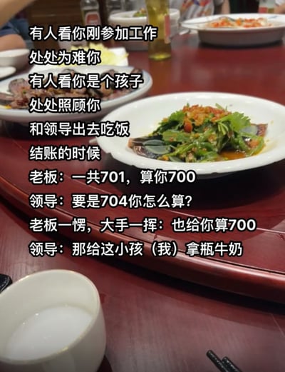 这张图片的背景是中式餐厅的红色圆桌桌面，桌面上摆放着凉拌皮蛋、腊味等菜品、装着饮品的容器、餐具等聚餐常见物品，仅在角落露出少量在场人员的肢体。图片上叠加了白色带黑边的文字，内容是一则暖心的职场小故事：刚参加工作的新人感慨职场上有人会因为你是新人故意为难，也有人会因为你年纪小多加照顾，随后讲述自己和领导外出吃饭的经历：结账时餐馆老板告知消费701元，主动抹零收700元，领导故意询问如果消费是704元会怎么算，老板表示同样抹零收700元，领导随即顺势要求老板给作为新人的自己拿一瓶牛奶，用巧妙的小玩笑为新人争取到了福利，体现了好领导对下属的关照。