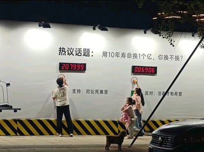 夜晚的街道上，一面大型白色墙壁上设置了一个引人深思的互动投票装置。墙上醒目地写着“热议话题：用10年寿命换1个亿，你换不换？”，下方分为“支持”和“反对”两个选项。支持方观点为“穷比死难受”，电子计数器显示已有207999票；反对方观点为“活着才有希望”，计数器显示6906票。一名男子正抬手按支持按钮，旁边有一位女子带着小女孩站在反对按钮区域，人行道上还有一只小狗和一辆黑色汽车。整个场景通过灯光照亮，营造出一种街头社会实验的氛围。
