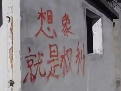 这是一张原始拍摄的静态单图，画面呈现了一面带有小窗口的老旧水泥墙面，墙面左侧有部分墙皮剥落的痕迹，墙面上用红色喷漆创作了“想象就是权利”的手写风格涂鸦文字，字体醒目，传递出强调想象具备重要价值的理念。