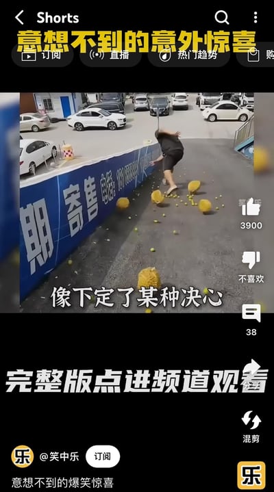 短视频截图中，一名女子在停车场靠近蓝色围墙处，地面散落多个黄色水果（疑似柚子或甜瓜），她正弯腰处理这一意外场景。画面上方有黄色大字标题“意想不到的意外惊喜”，中间叠加文字“像下定了某种决心”，底部提示“完整版点进频道观看”。界面显示点赞数3900，评论38条，来源账号为@笑中乐，带有订阅按钮和热门趋势标识，整体营造出生活中意外搞笑瞬间的氛围。