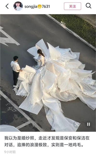 这是一张社交媒体内容截图，顶部显示发布者账号信息栏，主体俯拍画面为马路上堆放铺开大量白色褶皱片状物料，旁边站着一男一女两名穿白上衣的人员，乍看很像女子穿着裙摆极大的婚纱拍摄婚纱照，下方配文调侃称原本以为是浪漫的婚纱照场景，走近才发现是类似保安、保洁的工作人员在处理相关物料，想象中的浪漫背后实际是需要收拾的琐碎现实，形成强烈的反差感。