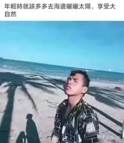 这是一张视觉错位类的搞笑梗图，图上方配有文字“年轻时就该多多去海边晒晒太阳，享受大自然”。画面中一名男子仰头闭眼，摆出陶醉享受的姿态，看似在海边惬意地晒太阳，但实际上他头顶类似棕榈树的影子是旁边的人用手比出的形状，形成了男子仿佛被“扇巴掌”的错觉，和配文的惬意感形成强烈反差，制造出搞笑效果。