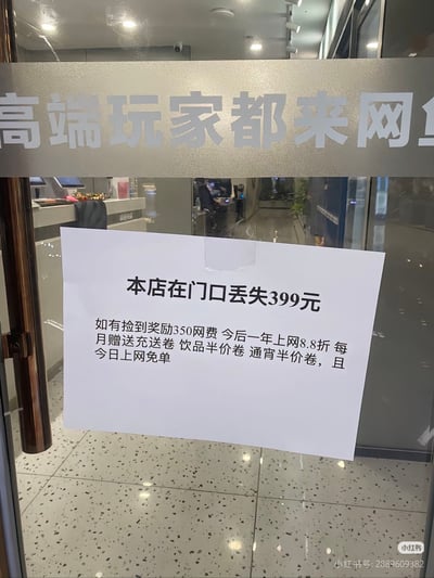 这是一张实拍的网吧玻璃门照片，玻璃门上部磨砂条印有“高端玩家都来网”的截断字样，门上贴有一张A4纸通知，声称门店在门口丢失399元，捡到的人可以获得350元网费、一年上网8.8折、每月充值券、饮品和通宵半价券、当日上网免单的奖励，实际上是商家的趣味营销套路：相当于用户支付399元即可获得上述全部权益，用玩梗的方式引导到店用户办理会员，右下角带有小红书发布者的水印信息。