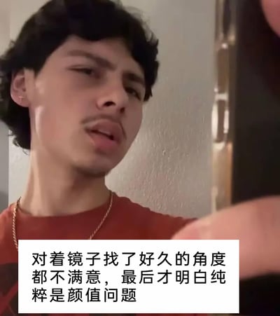 这是一张带文字标注的真人自拍梗图，图中男子穿着红色上衣，佩戴金色项链，对着镜子（镜头），脸上露出懊恼又无奈的神情，似乎在为自拍找不到好看角度而烦恼。图下方的配文写着“对着镜子找了好久的角度都不满意，最后才明白纯粹是颜值问题”，用自嘲的方式调侃自拍时的尴尬经历，内容搞笑又扎心，精准戳中很多人自拍时的同款困扰，容易引发强烈共鸣。