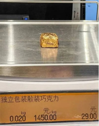 图片中展示了一块金色包装的Venchi巧克力放置在电子秤上，秤面显示该巧克力为独立包装散装巧克力，重量0.020公斤，单价1450.00元/公斤，总价29.00元。巧克力包装上清晰可见品牌名称“Venchi”，整体场景像是在商店的称重计价区域拍摄，突出了该巧克力的价格信息。