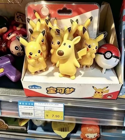 照片拍摄于商店玩具货架，主体是一盒标价7.90元的宝可梦皮卡丘玩偶。包装盒为红白配色，正面印有醒目的“宝可梦”字样、皮卡丘图案和精灵球标识，吸塑罩内可以看到多个黄色皮卡丘玩偶。盒子正前方放着一个哑光黄色的小狗造型玩偶：它有突出的棕色长鼻子、圆眼睛、直立尖耳朵和短小四肢，并不符合皮卡丘的官方形象。由于它身后正好有皮卡丘的闪电形尾巴，前后景在画面中重叠，乍看会像一个长着狗鼻子、狗耳朵的怪异皮卡丘。图中没有对白，笑点来自玩偶乱入和视觉错位，配合文案“根本没有这样的皮卡丘”，强调这个混搭形象并非真正的皮卡丘。