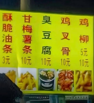 这是一张实拍街边小吃摊的价目招牌图片，招牌底色为亮黄色，竖向排列展示五种小吃的名称和价格，从左到右分别为：酥脆油条3元、甘梅薯条10元、臭豆腐10元、鸡叉骨10元、鸡柳10元，每种小吃下方都配有对应食物的预览小图；将每列菜品的第一个字横向连读，得到“酥甘臭鸡鸡”，形成低俗谐音梗，图片左下角有拍摄时的黑色遮挡物，遮挡了部分油条的预览图。
