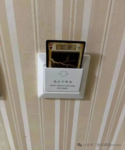 一张酒店房间内的照片，展示了一个白色的感应卡取电装置。装置上有中英文提示文字'感应卡取电 INSERT CONTACTLESS CARD FOR POWER'。然而，插入取电槽的并非正规房卡，而是一张红桃Q扑克牌，牌面上印有'闪电'字样和闪电图案，形成了有趣的视觉反差和幽默效果。