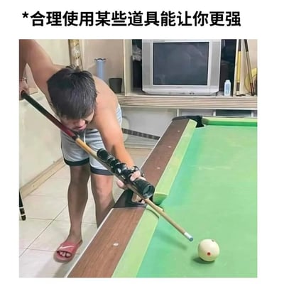 整张图为顶配底文的图文混排搞笑图，顶部文字标注“*合理使用某些道具能让你更强”，下方实拍画面中，一名赤裸上身、穿灰色短裤与粉色拖鞋的男子正俯身准备打台球，他在普通台球杆的前端额外加装了类似枪械瞄准镜的配件，正借助该配件瞄准台球，将枪械瞄准的逻辑用在台球运动上，以离谱的改造操作形成搞笑反差感。