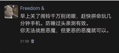 黑色背景的社交媒体截图，左侧配有一张泰迪熊的小图，上方显示“Freedom &”字样。主要文字内容为：“早上关了闹铃千万别闭眼，赶快拼命玩几分钟手机。防睡过头亲测有效。你无法战胜恶魔，但更恶的恶魔就可以。” 底部左侧有时间“21:58”及垃圾桶图标。内容以幽默比喻的方式分享了一个防止睡过头的生活小技巧，将“玩手机”比作“更恶的恶魔”来对抗“睡意恶魔”。