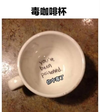 这是一张俯拍视角的图片，展示了一个白色咖啡杯放置在棕色纹理桌面上。杯子内部底部有手写风格的文字，上方为英文“you've been poisoned.”，下方为中文“你中毒了”，整体营造出一种幽默调侃的氛围，仿佛在以“中毒”为噱头进行玩笑。