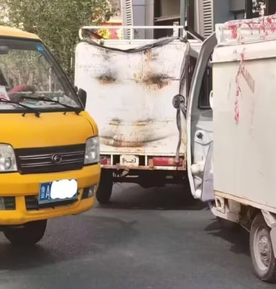 图片展示了街头一幕：左侧是一辆黄色面包车，车牌号为鲁A（推测来自山东济南），右侧是一辆白色卡车，车身有明显的锈迹和疑似烧灼的痕迹，车门呈打开状态。背景可见树木和建筑物，整体呈现真实的城市街景氛围。