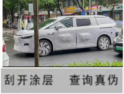 这是一张上下拼接的玩梗图文，上半部分是在城市街道场景中拍摄的一辆MPV车型，车身覆盖着黑白波浪纹的伪装贴纸，这类贴纸是汽车厂商在新车正式发布前进行道路测试时，用来隐藏车辆外观细节设计的常用手段；下半部分是模仿商品防伪标签的提示文字“刮开涂层 查询真伪”，将新车伪装的神秘感与防伪标签的“刮开见真容”进行结合，形成趣味玩梗效果，调侃想要知晓这款新车的真实外观，就像刮开涂层查询真伪一样需要“解锁”。