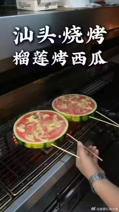 图中展示的是汕头地区的创意烧烤吃法——榴莲烤西瓜：两块带外皮的厚切西瓜被放在炭火烧烤架上，西瓜果肉上铺着榴莲果肉，一只手正用筷子翻动西瓜，对其进行烤制。这种将两种水果结合进行烧烤的料理方式打破了大众对烧烤食材的常规认知，属于新奇的“黑暗料理”，既让人感到新鲜好奇，也对其最终的口味充满疑惑。