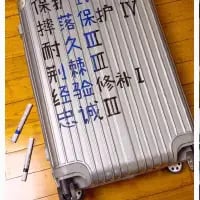 这是一张竖版拍摄的银色行李箱照片，行李箱表面用深色马克笔手写了多组类似部队装备标识的标语，内容包括“保障 排刺 经 忠诚”“筑 淬火 练 验 诚”“保护 Ⅲ 修 补”，还有罗马数字“IV”“I”“Ⅲ”。画面左下角放着两支马克笔，显然是完成手写创作后拍摄的记录，将日常行李箱改造成带有硬核部队风格的样子，充满反差趣味。
