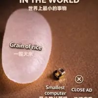 这张图通过将一粒普通大米和号称“世界上最小的电脑”的微型电子设备并列放置，进行直观的尺寸对比，以此展现该微型电脑的极小体积。图中配有中英文结合的文字标注，上方英文为“IN THE WORLD”，对应中文“世界上最小的事物”；大米旁标注“Grain of rice 一粒大米”，微型设备旁标注“Smallest computer”，右下角还有“CLOSE AD”的按钮，说明这是一则带有广告属性的科普展示内容，用大众熟悉的大米作为参照，让观看者能轻松理解这款微型电脑的微型化程度。