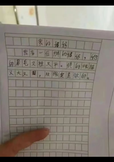 这是一张翻拍小学生手写作文的静态图片，作文标题为《我的妈妈》，以孩子的视角直白地描述了妈妈的外貌：“我有一位胖的妈妈，她的眉毛又粗又平。她的眼睛又大又圆，双眼皮是做的。”，文字充满童真，毫无修饰地说出了真实细节，图片下方还露出了一根手指，整体画面朴素却因孩子的直白话语显得十分有趣。