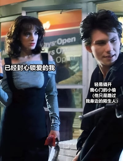 图片展示了一个电影场景，左侧是一位穿着蓝色上衣和黑色背带裤的女性，手持疑似带血的刀，表情冷峻。右侧是一位穿着黑色夹克的男性，表情惊讶地转头看向女性。图片上叠加了文字："已经封心锁爱的我"和"轻易撬开我心门的小偷 (他只是路过我身边的陌生人)"，表达了一种情感矛盾的状态。