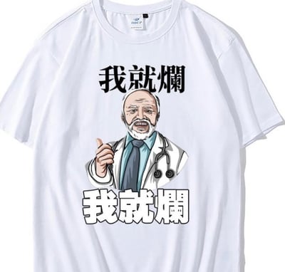 一张白色T恤的设计图，T恤正面印有卡通风格的医生形象：一位白发白胡子的老者穿着白色医生外套，脖子上挂着听诊器，右手竖起大拇指，嘴巴张开呈喊话状。医生形象上方有黑色粗体文字“我就爛”，下方有白色粗体带黑色描边的文字“我就爛”。整体风格轻松幽默，通过医生的权威形象与“摆烂”文字形成反差萌，表达一种自嘲式的轻松态度。
