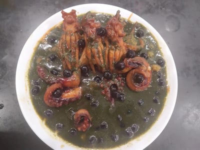 这是一盘家常烹制的豆豉烧笔管鱼（小鱿鱼），深绿色的浓稠汤汁里浸泡着烹制入味的笔管鱼，表面散落着乌黑的豆豉，笔管鱼呈现出炖煮后的红棕色，看起来酱香浓郁，是一道风味十足的海鲜家常菜。