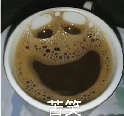 图片展示了一杯咖啡的特写镜头，白色咖啡杯内盛有深棕色的咖啡，表面的泡沫自然形成了一个类似笑脸的图案——两个圆形的白色泡沫区域如同眼睛，下方的弧形凹陷则构成嘴巴。杯底位置叠加了白色文字“苦笑”，形成视觉与文字的有趣结合：看似微笑的泡沫表情被文字定义为“苦笑”，营造出一种反差感，仿佛咖啡也在表达无奈的情绪。