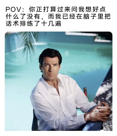 这是一张贴合社交心理的真人梗图，主体是爱尔兰男演员皮尔斯·布鲁斯南的写真照片，画面中他身着白色衬衫，坐在泳池边，双手交握放在腿上，表情严肃地直视镜头，神态沉稳。图片上方配有中文文字“POV：你正打算过来问我想好点什么了没有，而我已经在脑子里把话术排练了十几遍”，用这位以沉稳特工形象深入人心的演员的严肃神态，反差感地诠释了人们在即将面临他人询问时，内心早已反复演练回答话术的紧张状态，精准戳中了人们在社交场景中提前预演对话、避免出错的普遍心理。