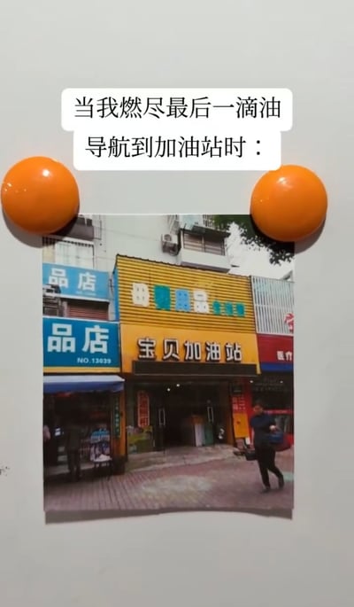 图片上方配有文字'当我燃尽最后一滴油导航到加油站时：'，下方是一张实拍的街道店铺照片。照片中央店铺的黄色招牌上写着'宝贝加油站'，但实际是一家售卖商品的普通店铺（非燃油加油站），通过名称的巧合制造出导航到错误地点的幽默效果，展现了司机在燃油耗尽后导航到'加油站'却发现是普通商店的无奈又搞笑的场景。