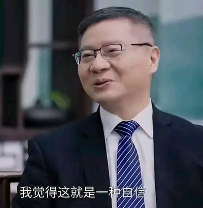 这是一张视频截图，画面中是一位穿着深色西装、白衬衫搭配蓝白条纹领带的中年男士，他戴着眼镜，面带温和的微笑，正坐着发表观点，画面下方配有白色字幕“我觉得这就是一种自信”，整体构图清晰，场景偏向正式的访谈或演讲场合。