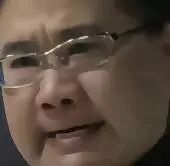 图片为一张人物面部特写，主体为一位戴着眼镜的人物，面部表情较为平和，背景模糊未显示具体环境。