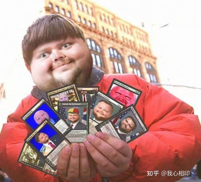 图片中一名穿着红色外套的男子，面带惊讶表情，双手捧着一叠设计成 trading card 风格的搞笑表情包卡片。每张卡片上都印有不同人物的夸张面部表情，部分卡片上可见英文文字。背景是一栋具有古典风格的多层建筑，可能是在城市街道上拍摄。图片通过将真人照片与虚构的搞笑卡牌结合，创造出幽默效果。