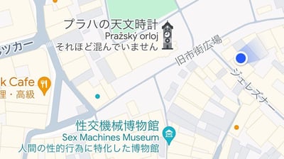 这是一张日文版的布拉格老城区域导航地图截图，标注了两处知名景点：上方的**布拉格天文钟（Pražský orloj）**，附带说明「それほど混んでいません」（意为“没有那么拥挤”）；下方的**性机器博物馆（Sex Machines Museum）**，标注说明为「人間の性的行為に特化した博物館」（意为“专门聚焦人类性行为的博物馆”）。同时地图还标注了一家标注为「高級」的k Cafe餐厅，以及旧市街広場、ジェレズナー街道等区域信息，景点名称同时配有日文、英文、捷克文的多语言标注，方便日本游客识别。