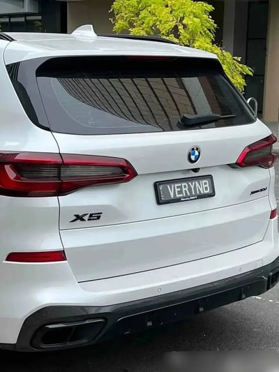 这是一张BMW宝马X5汽车的背面照片，最吸引眼球的是其个性化车牌“VERYNB”，这个英文组合谐音“Very 牛B”，意味着“非常牛逼”、“厉害”的意思，在网络语言中被广泛使用，属于带有明显双关与谐音梗的表达。

牌照的幽默和炫耀意味十足，既展示了车主对于自己座驾的自信，也提醒观看者这是台“很牛”的车，常见于社交网络上展示个性与幽默感的内容。