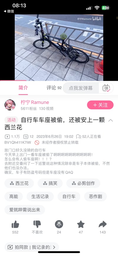 这是一张Bilibili视频页面的截图，展示了一个有趣的生活事件。视频缩略图显示一辆黑色自行车停靠在路边栏杆旁，其车座被人偷走并替换成了一颗西兰花，形成了强烈的视觉反差和幽默感。页面显示视频标题为“自行车车座被偷，还被安上一颗西兰花”，发布者为“柠宁Ramune”，发布时间为2023年6月26日。视频描述中，作者表达了发现车座被盗并被恶搞的惊讶和无奈情绪，提到即使报警也因未涉及整车被盗而难以处理的情况。页面还显示了视频的播放量、评论数等互动数据，以及相关的标签分类。