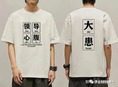图片展示一件梗T恤，正面分4格写有“领导腹心”并用拼音和英语注释。背面为两格“大患”，均有拼音。这设计模仿周期表，带英文装酷气息。“领导腹心”意为被信任的助手，但背面“大患”即“祸害”，构成反转双关，自嘲讽刺意浓，十分适合职场调侃。