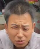 图片中是一位短发男性，他眉头微皱，眼神略带迷茫，嘴巴微张，整体表情看起来有些困惑和无奈。背景有模糊的物品，可能是室内环境。
