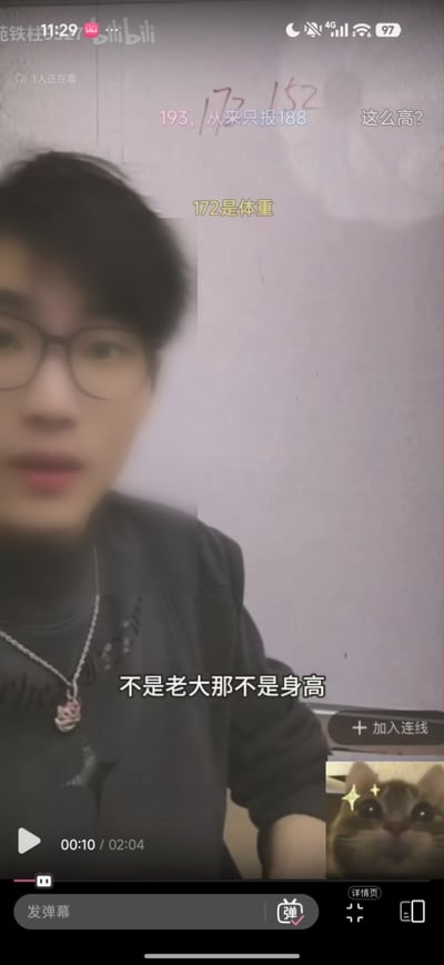 这是一张B站竖屏直播的界面截图，画面左侧是佩戴黑框眼镜、穿深色上衣搭配银色项链的男主播，画面上叠加了多条观众发送的弹幕，有观众误将数字172当成主播的身高发出疑问，后续弹幕补充说明172其实是主播的体重，主播也在画面下方配上字幕澄清“不是老大那不是身高”，画面右下角显示了连麦方的星星眼呆萌猫咪头像，界面还带有B站直播的播放进度条、发弹幕按钮、加入连线按钮等常规功能标识。